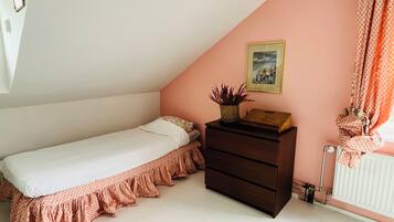 A bedroom with a single bed, a dresser, a radiator, and a framed picture on the wall.