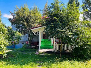 Una casa pequeña con puerta verde, un porche y una escalera que sube a la entrada.