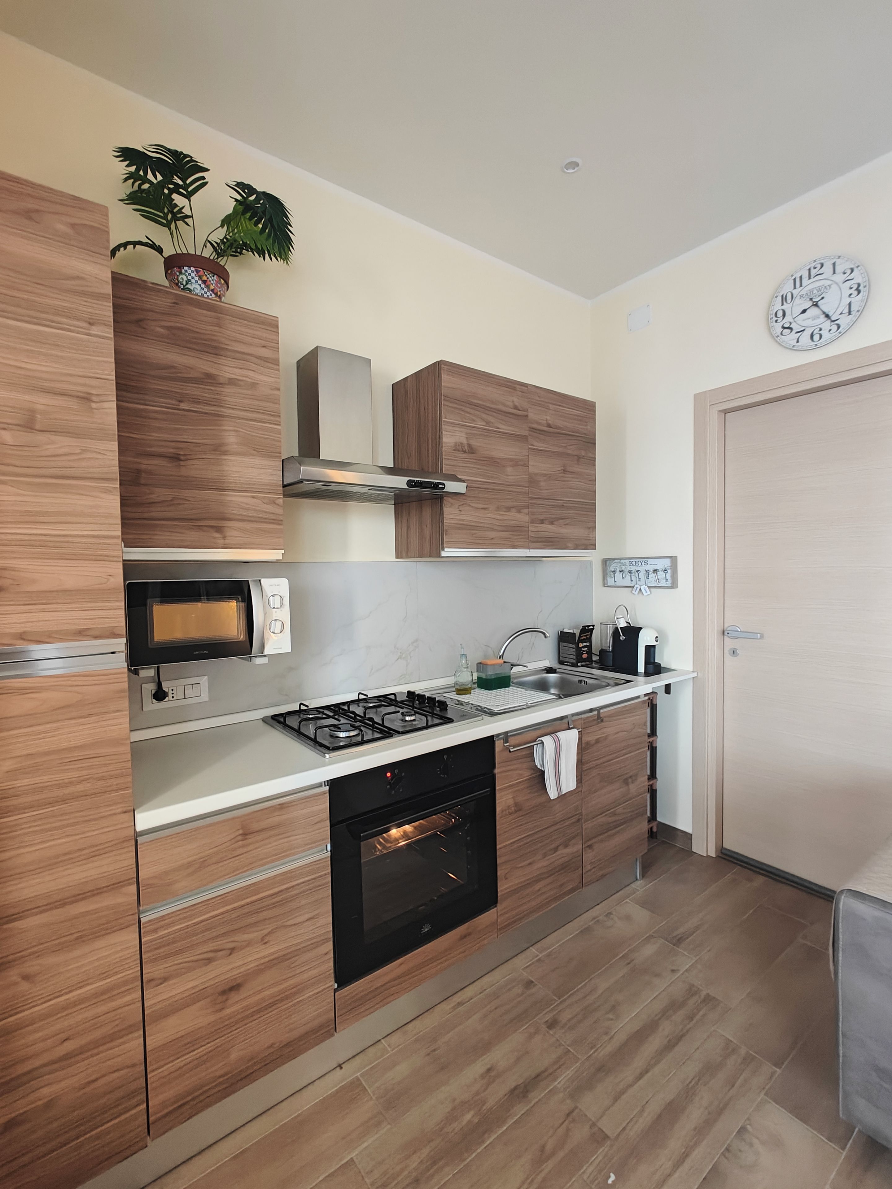 A modern kitchen with wooden cabinets, a built-in microwave, a gas stove, and a stainless steel range hood.