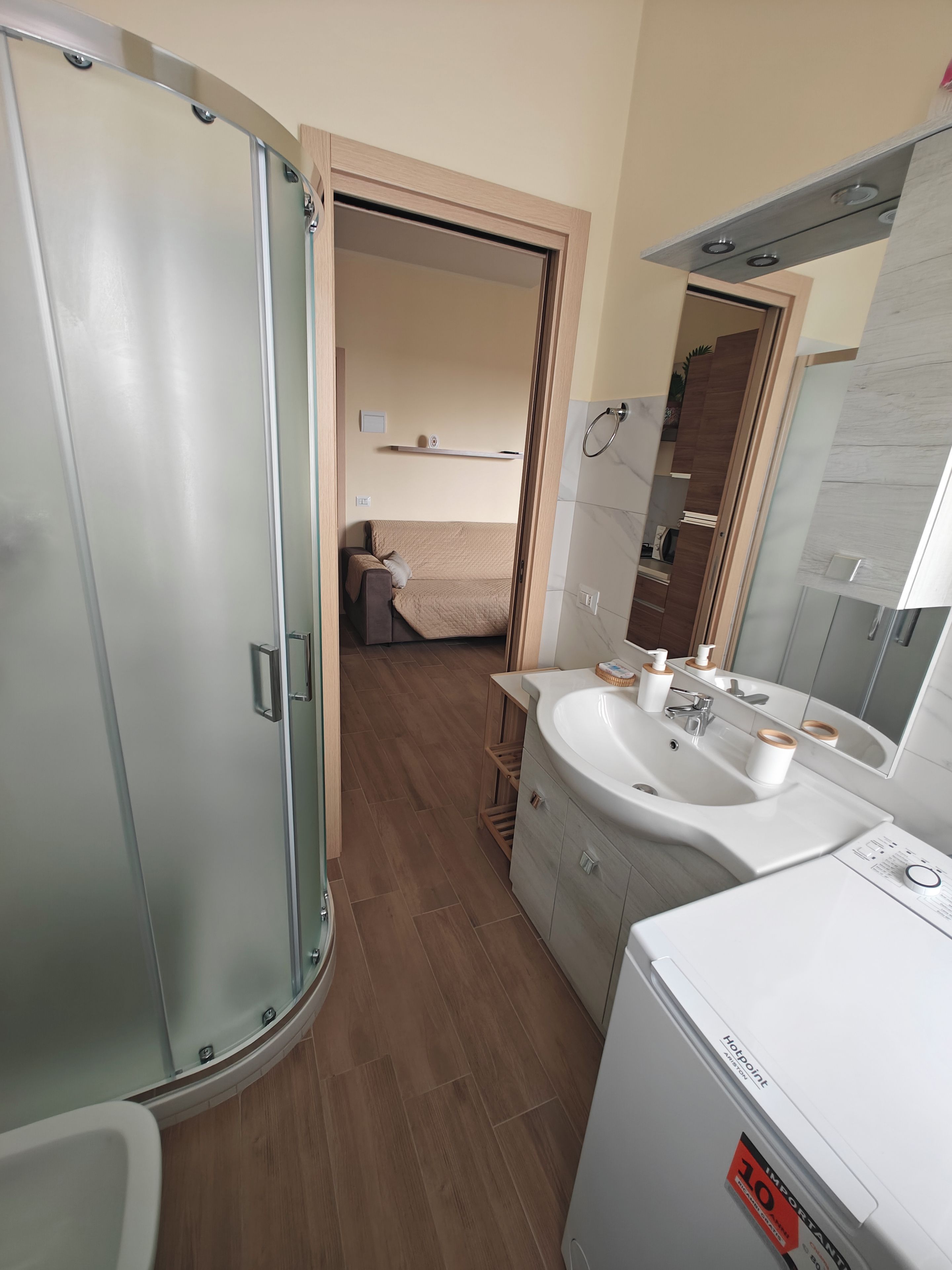 A modern bathroom with a glass shower enclosure, a sink with a mirror, and a toilet.