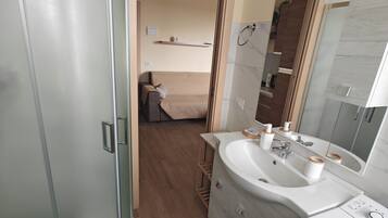 A modern bathroom with a glass shower enclosure, a sink with a mirror, and a toilet.