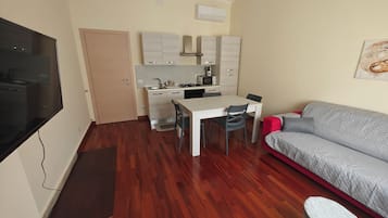 A compact living space with a kitchenette, a dining area, a sofa, and a television.