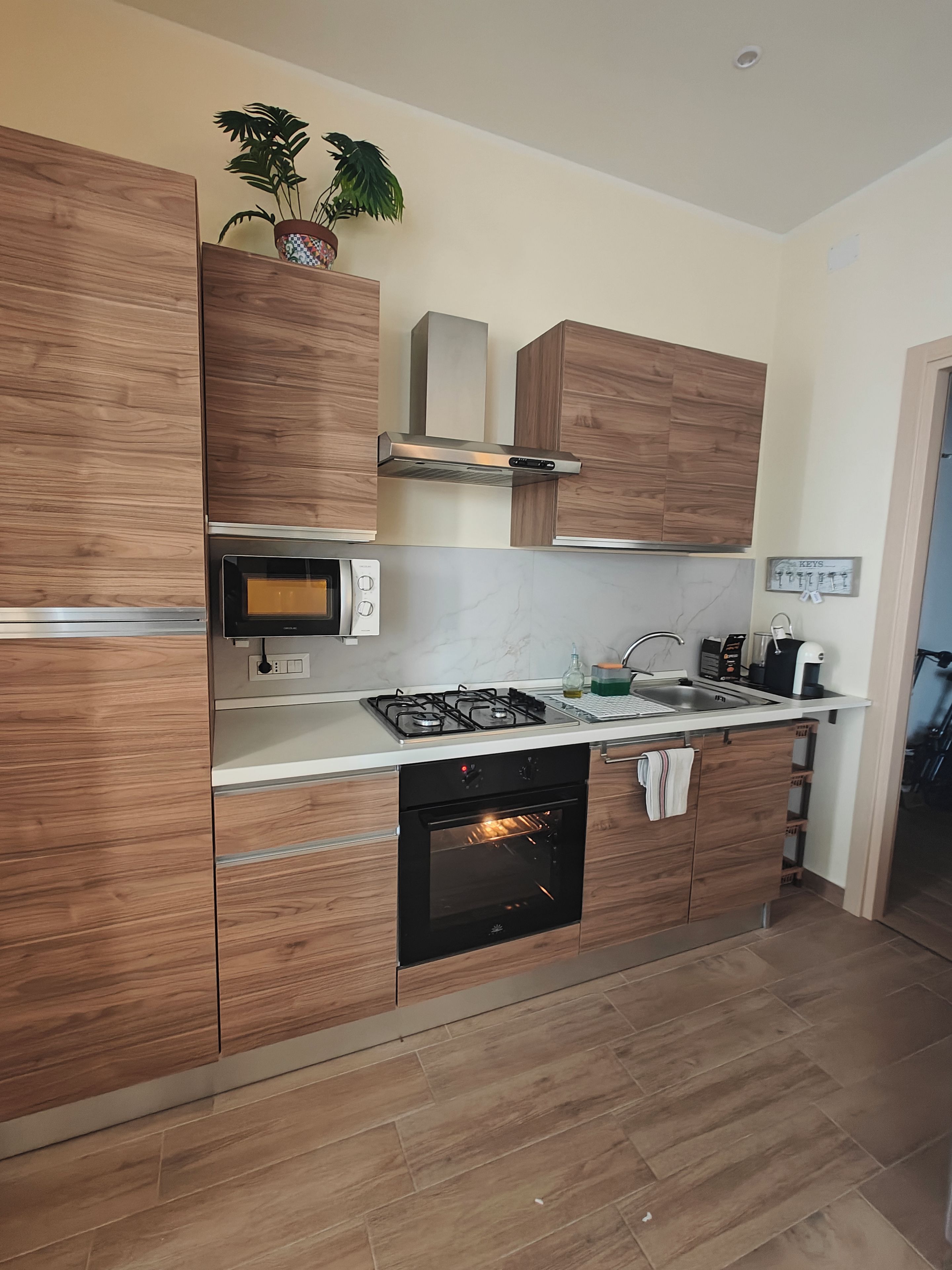 A modern kitchen with wooden cabinets, a built-in oven, a microwave, and a gas stove.