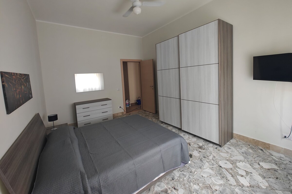 Ein Schlafzimmer mit Bett, Kleiderschrank, Fernseher und Deckenventilator.