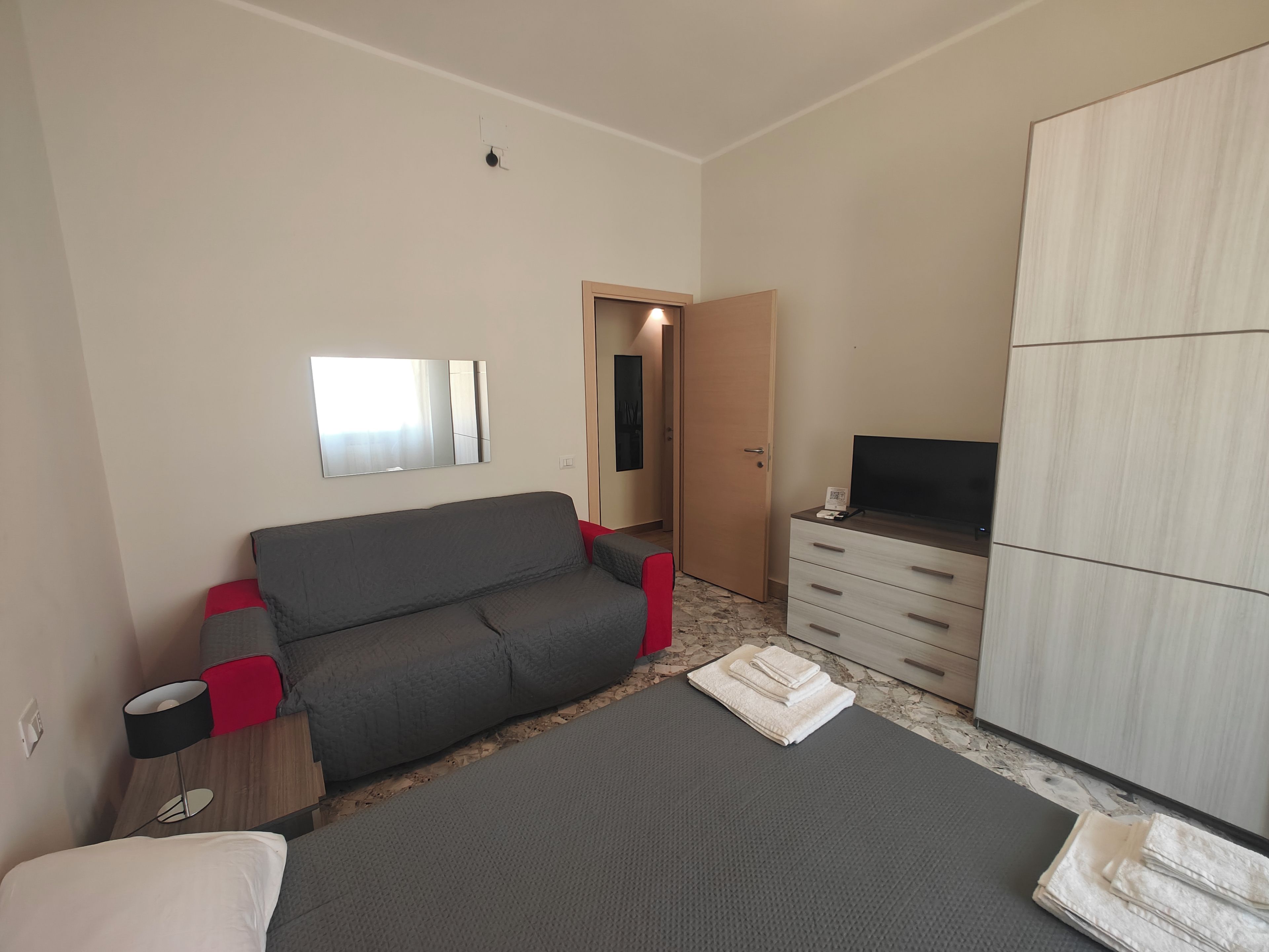 Ein Hotelzimmer mit Sofa, Fernseher, Kleiderschrank und Bett.