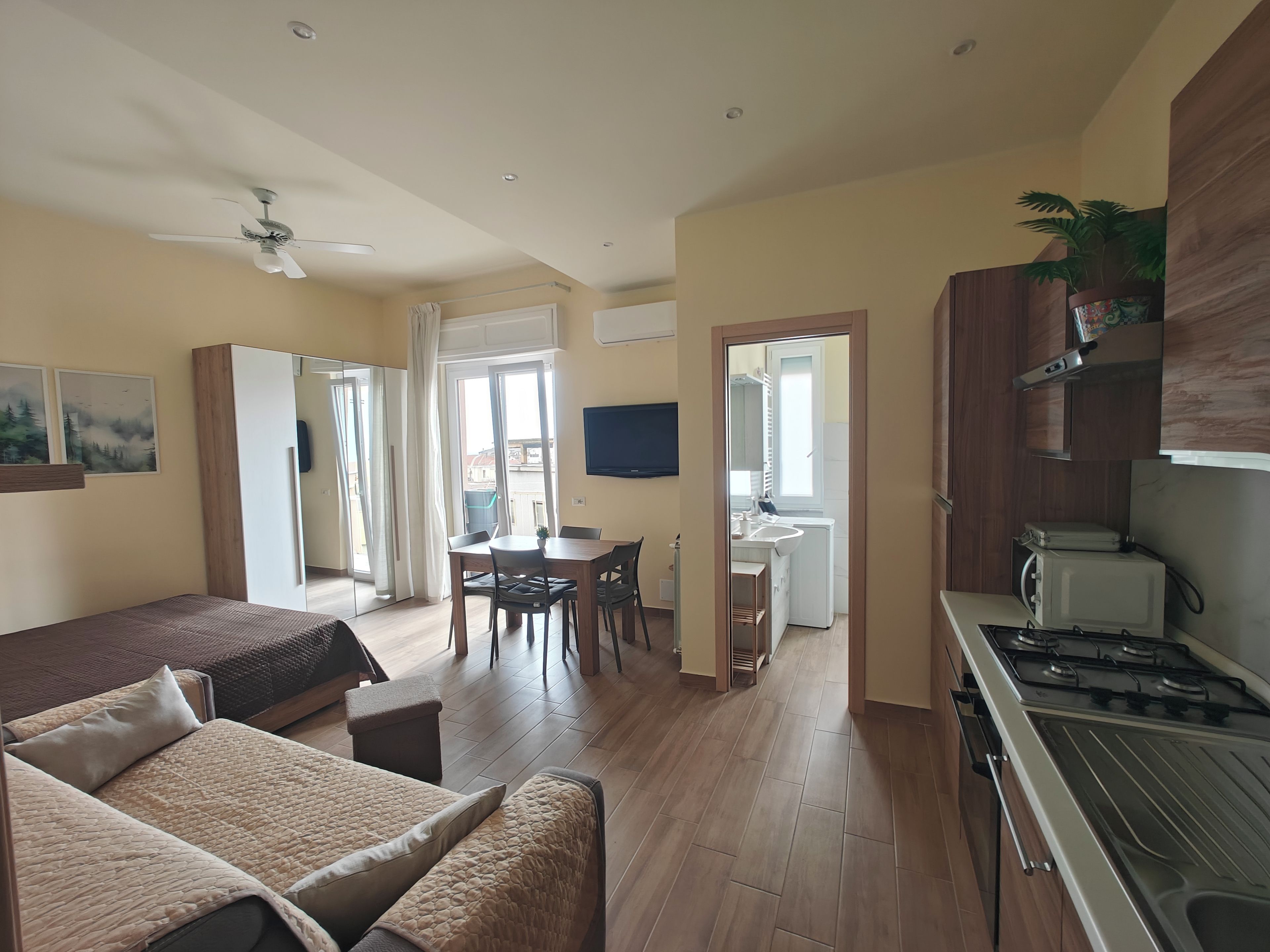 A modern living room with a sofa, a dining table, and a kitchen area with a stove.
