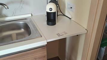 Une cuisine équipée d’un évier en acier inoxydable, d’une machine à café et d’une prise électrique murale.