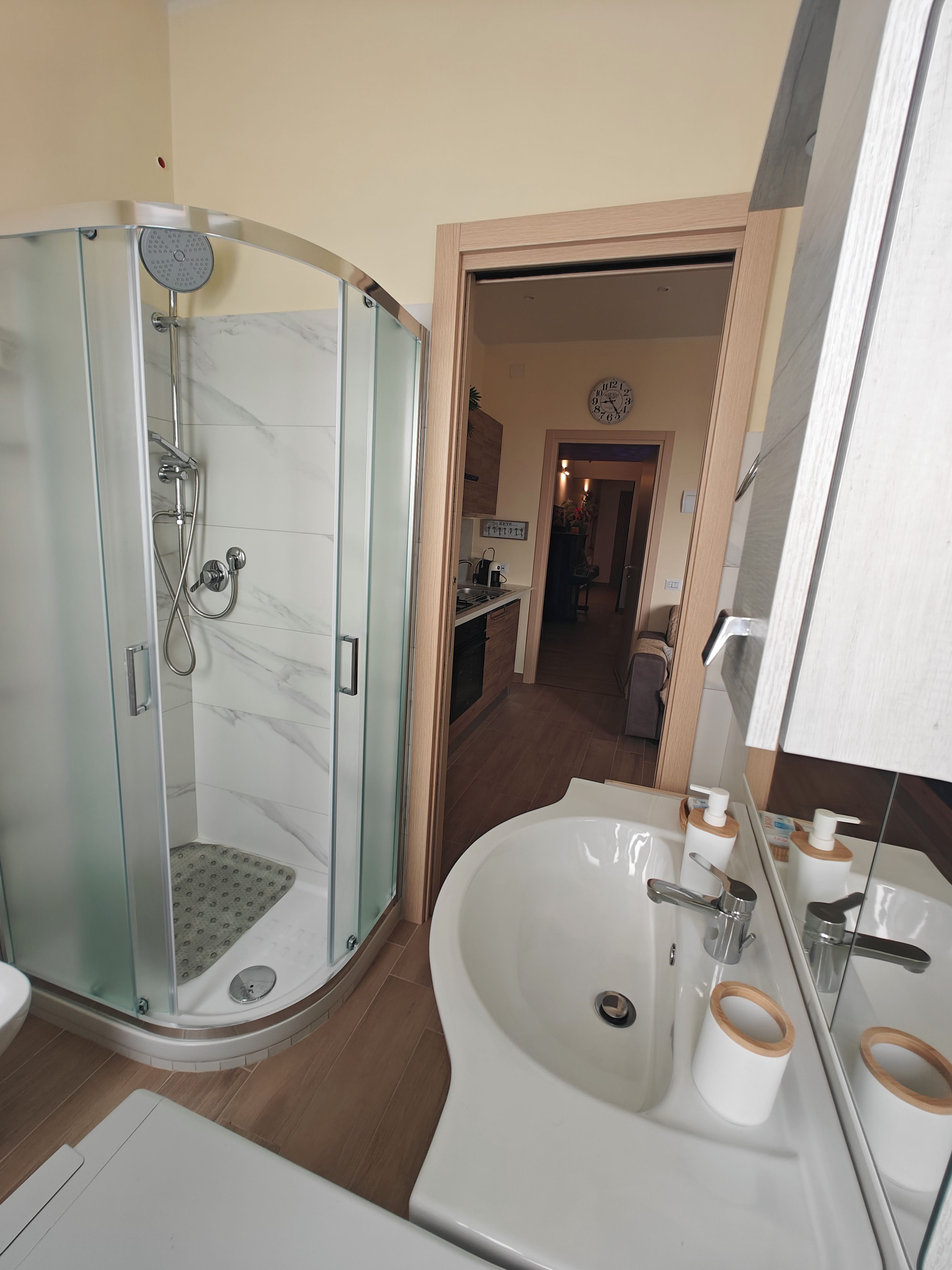 Een moderne badkamer met een douchecabine van glas, een vrijstaand bad en een wastafel met spiegel.