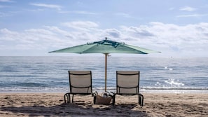 Two beach chairs under a beach umbrella facing the ocean. - Ocean View Escape: 2BR Villa at Marriott’s Oceana Palms (Riviera Beach)