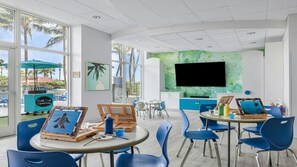 A bright, modern art studio with large windows, blue chairs, and art supplies. - Ocean View Escape: 2BR Villa at Marriott’s Oceana Palms (Riviera Beach)