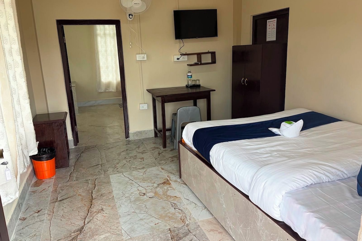 Een hotelkamer met een bed, een bureau, een stoel, een televisie en een kledingkast.