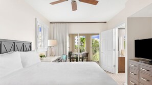 Ein Hotelzimmer mit einem großen Bett, einem Deckenventilator, einem Fernseher, einem Balkon mit Tisch und Stühlen sowie Blick ins Freie.