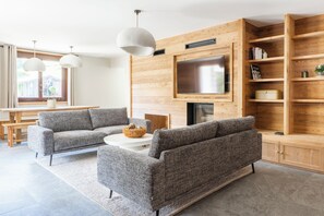 A modern living room with a sectional sofa, a coffee table, and a TV mounted on a wooden wall. - Marion's Chalet, surrounded by nature, 15 minutes from Chamonix (Vallorcine)