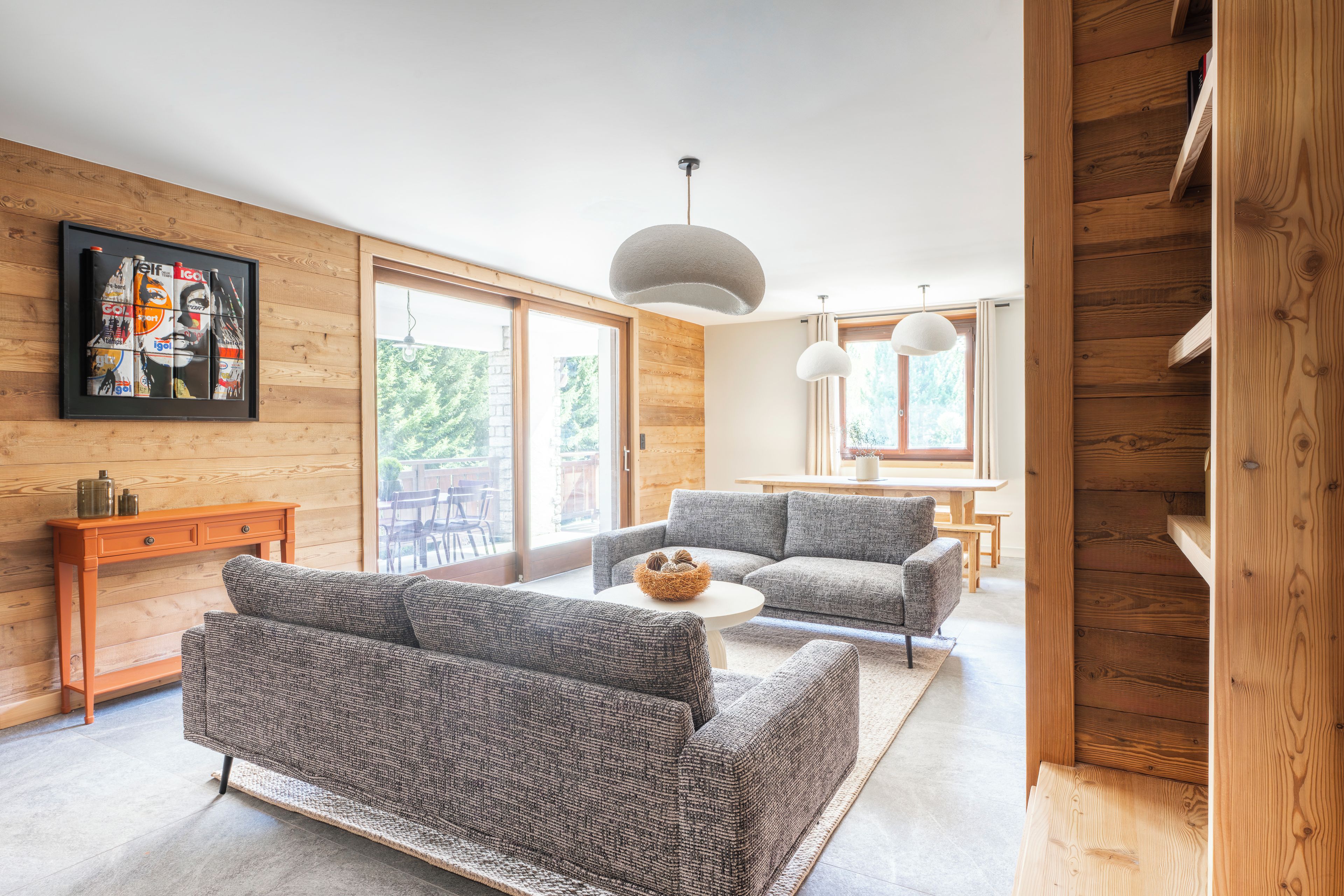 Un salon moderne avec un canapé gris, une table basse en bois et une grande fenêtre.