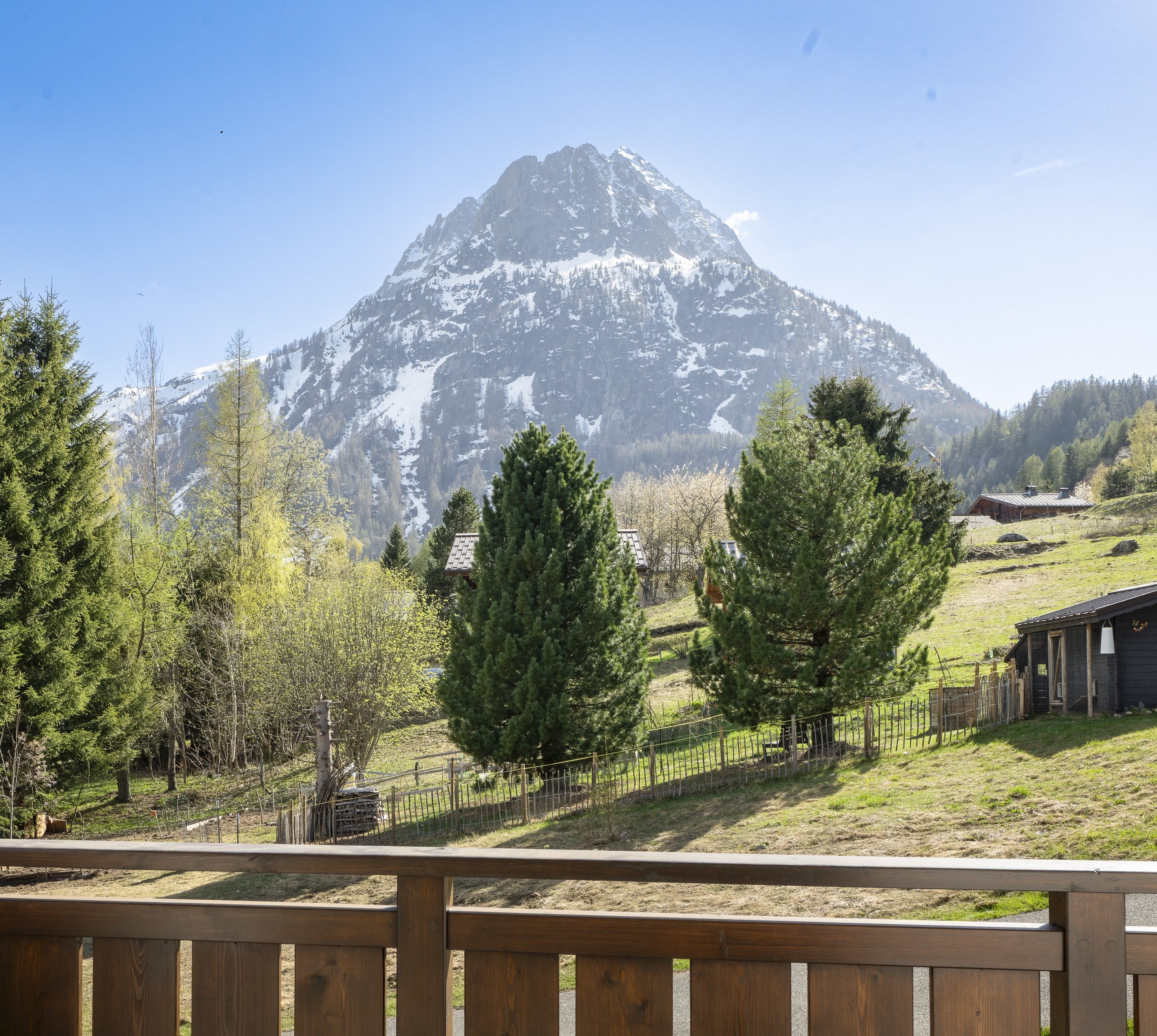 A mountain landscape with a wooden fence in the foreground.