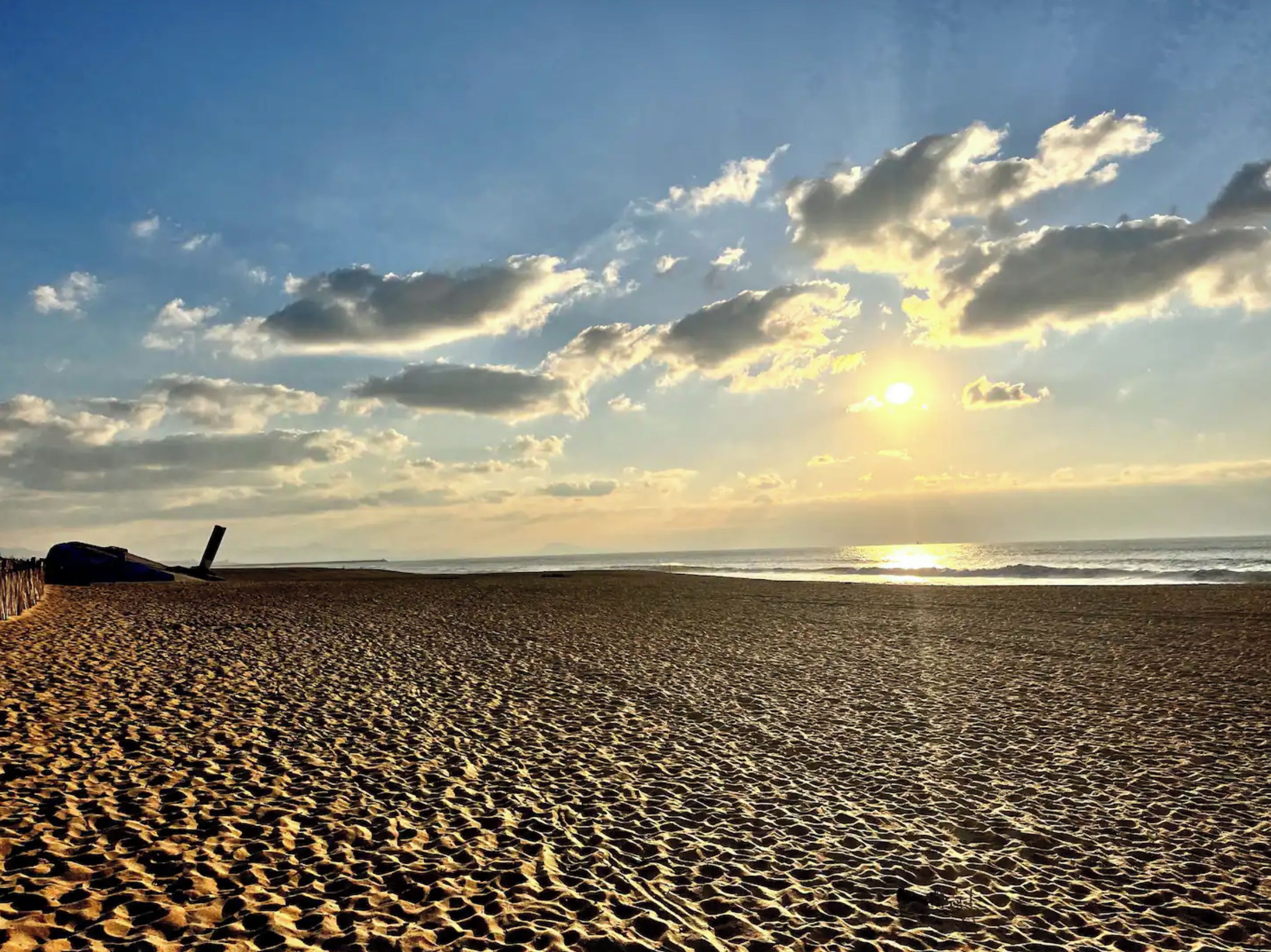 Una playa con cielo despejado y el sol poniéndose o saliendo.