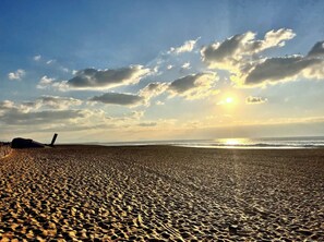 Una playa con cielo despejado y el sol poniéndose o saliendo.