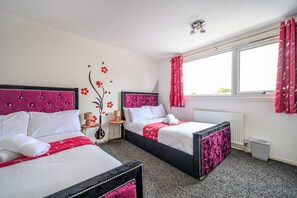 Une chambre d’hôtel avec deux lits, un radiateur, une fenêtre avec des rideaux et un élément décoratif sur le mur.