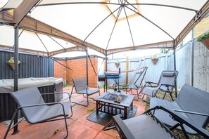Une terrasse extérieure dotée d’un espace salon couvert, d’un barbecue et d’un foyer.