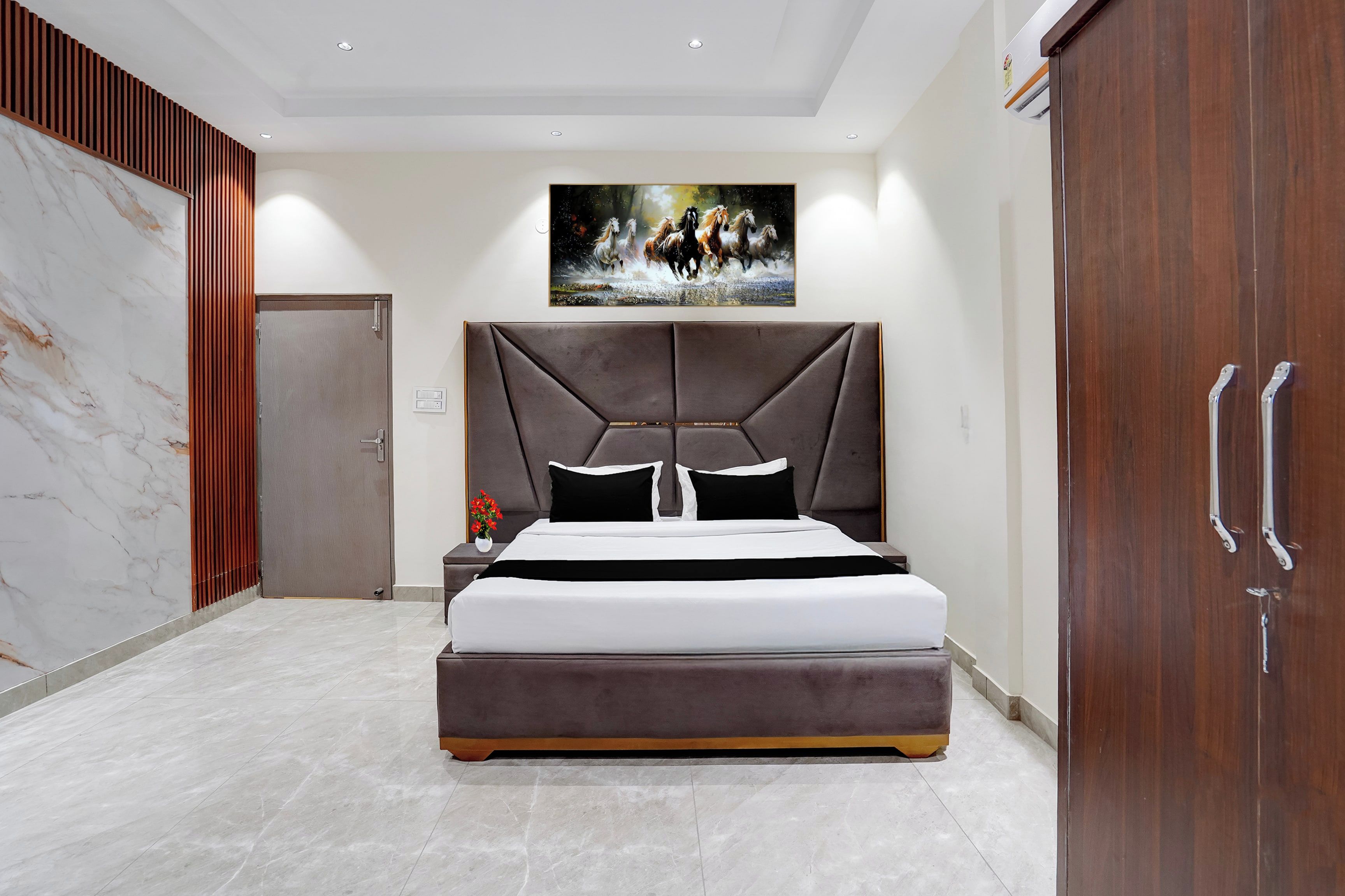 Un dormitorio moderno con una cama grande, cabecera, mesita de noche, un cuadro y un armario.