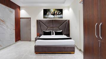 Un dormitorio moderno con una cama grande, cabecera, mesita de noche, un cuadro y un armario.
