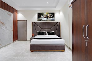 A modern bedroom with a large bed, a headboard, a nightstand, a painting, and a wardrobe.