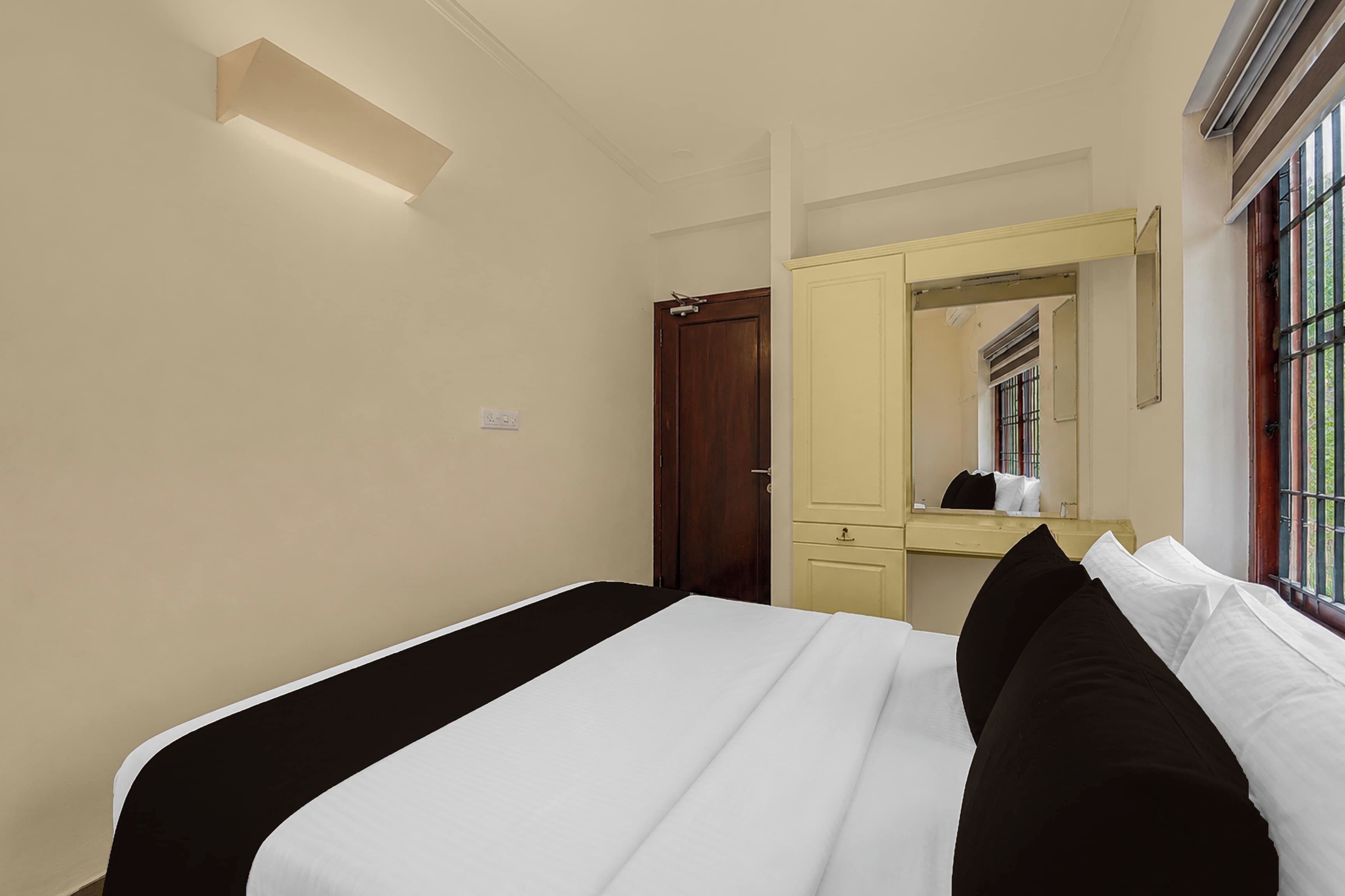 Een hotelkamer met een bed, een kledingkast, een spiegel en een raam.