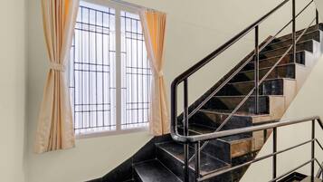 A staircase with metal railings and a window with curtains.