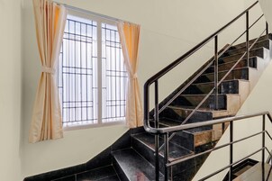 Una escalera con barandillas metálicas y un ventanal con cortinas.