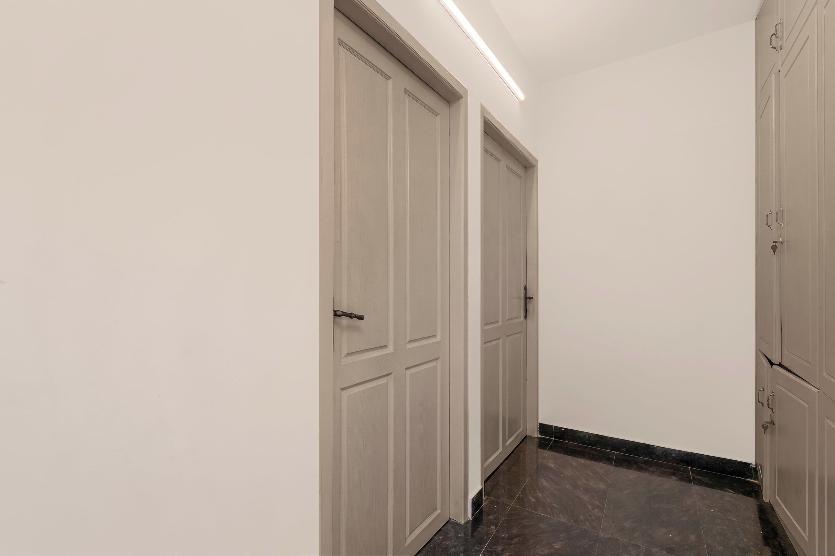 Un pasillo con dos puertas cerradas y una lámpara en el techo.
