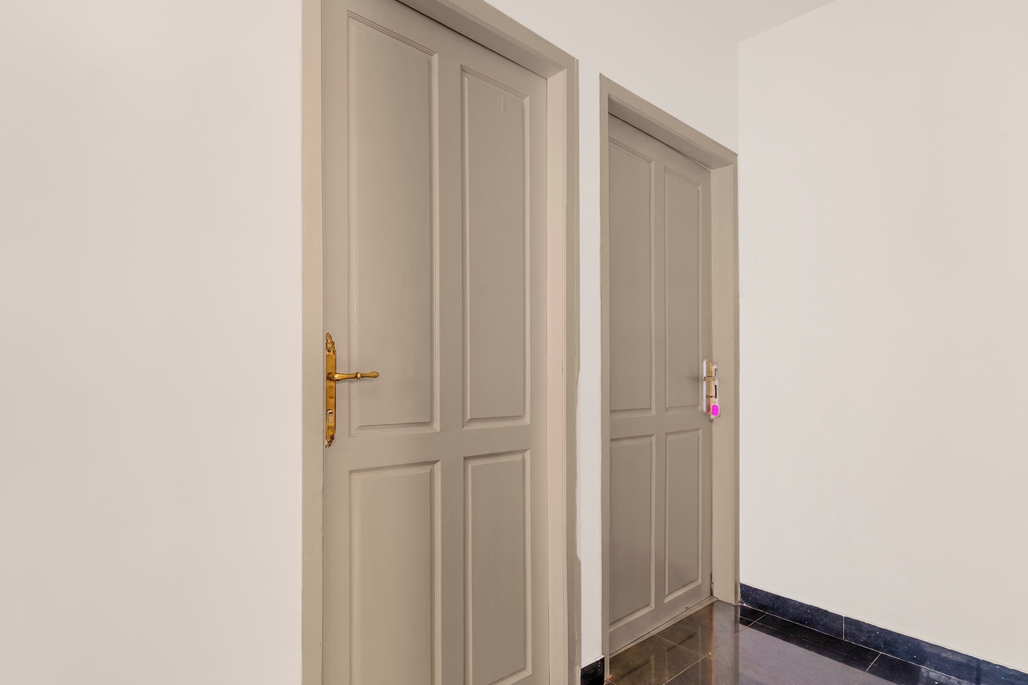A hallway with two closed doors, one with a brass handle and the other with a modern electronic lock.