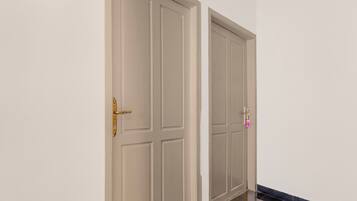 A hallway with two closed doors, one with a brass handle and the other with a modern electronic lock.