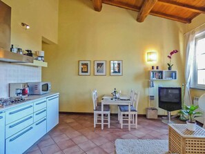A compact kitchen with a dining area, a microwave, a coffee machine, and a TV. - Lucca apartment with private furnished terrace (Lucca)