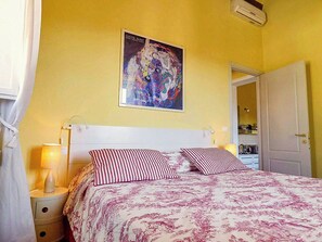A bedroom with a bed, a nightstand, a lamp, a door, and a wall-mounted poster. - Lucca apartment with private furnished terrace (Lucca)