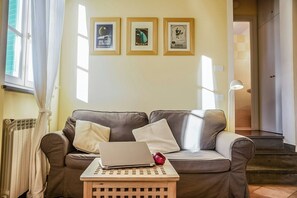 A living room with a sofa, a laptop, and a small table. There are three framed pictures on the wall. - Lucca apartment with private furnished terrace (Lucca)