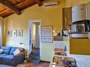 A compact living space with a kitchenette, a sofa, and a framed menu on the wall. - Lucca apartment with private furnished terrace (Lucca)