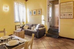 A living room with a sofa, a dining table set for two, and a staircase leading to another room. - Lucca apartment with private furnished terrace (Lucca)