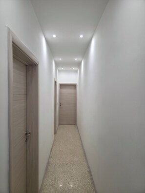 Ein schmaler Flur mit einer Holztür links und einer verschlossenen Tür am Ende.