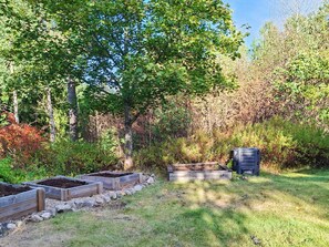 Ein Garten mit erhöhten Beeten und einer Komposttonne.
