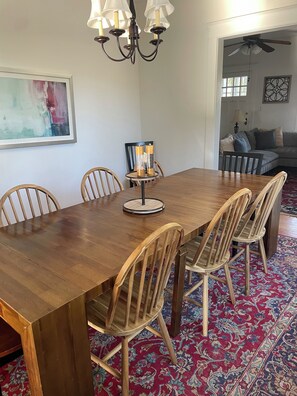 Een eetruimte met een houten tafel, stoelen, een kroonluchter en een kamerbreed tapijt.