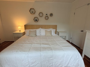 A large bed with a quilted white duvet, two bedside tables with lamps, and a wooden headboard. - Spa Creek Cottage – Walk to Downtown Annapolis (Annapolis)