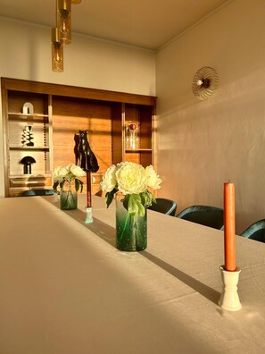 A dining table with vases of flowers and a candle, wooden shelves with decorative items, and a ceiling fan. - Diamant - Exclusive Villa (Funchal)