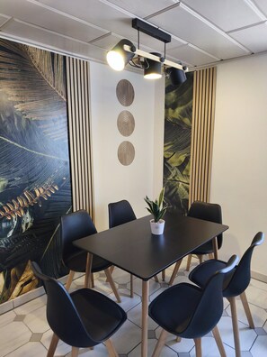 Et mødelokale med et mørkt bord, seks stole, en potteplante og et stort abstrakt vægmaleri.