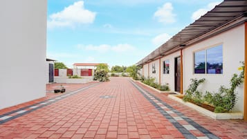 Un camino pavimentado que conduce a un edificio con techo rojo y una puerta señalizada con 'EXIT'.