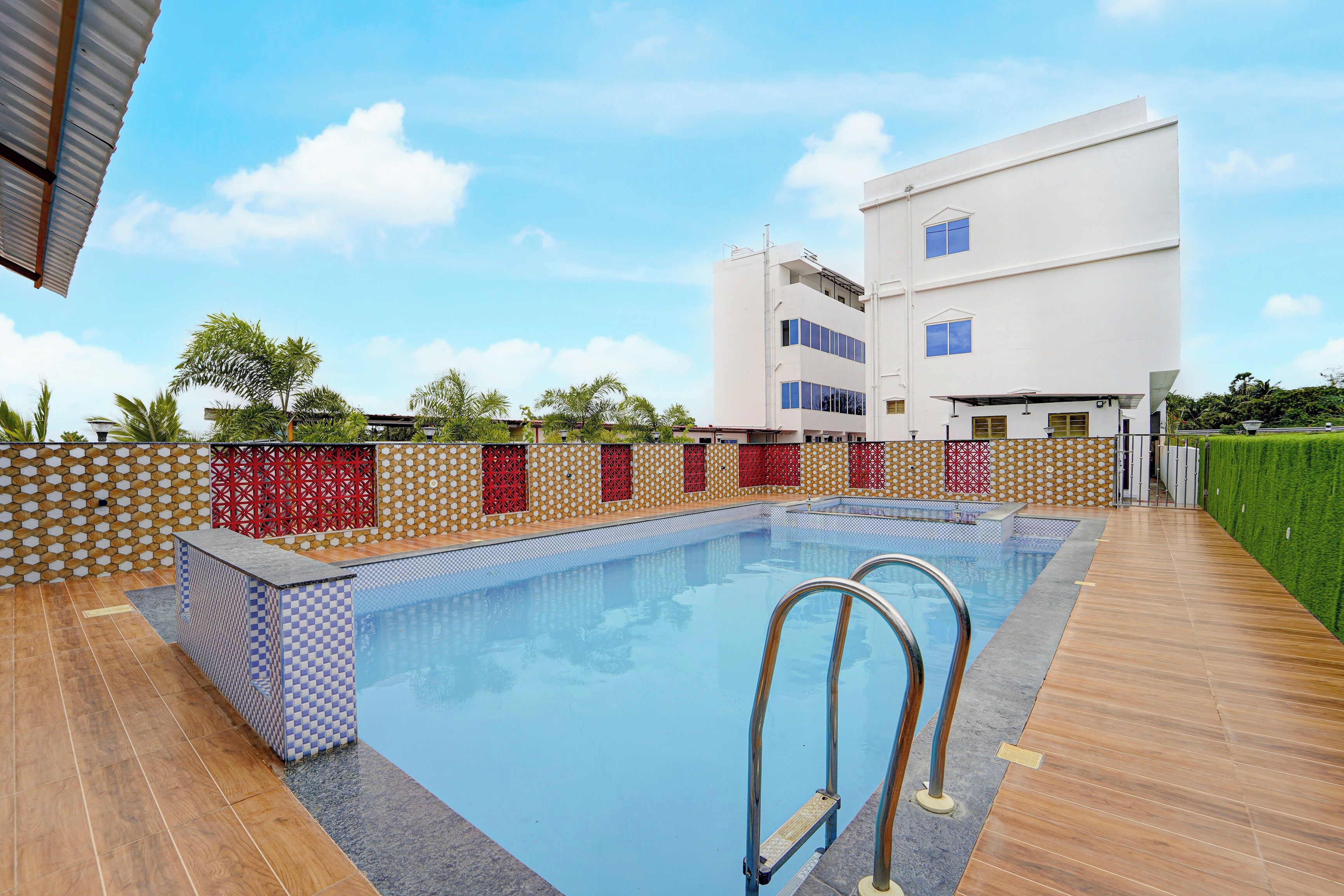 Una piscina con cubierta de madera, rodeada por un muro bajo con baldosas decorativas.