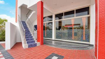 Un edificio moderno con área de recepción, una escalera con escalones de mármol y una paleta de colores rojo y blanco.