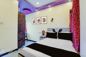 Un dormitorio moderno con una cama, una mesita de noche, un florero con flores y decoración en la pared.