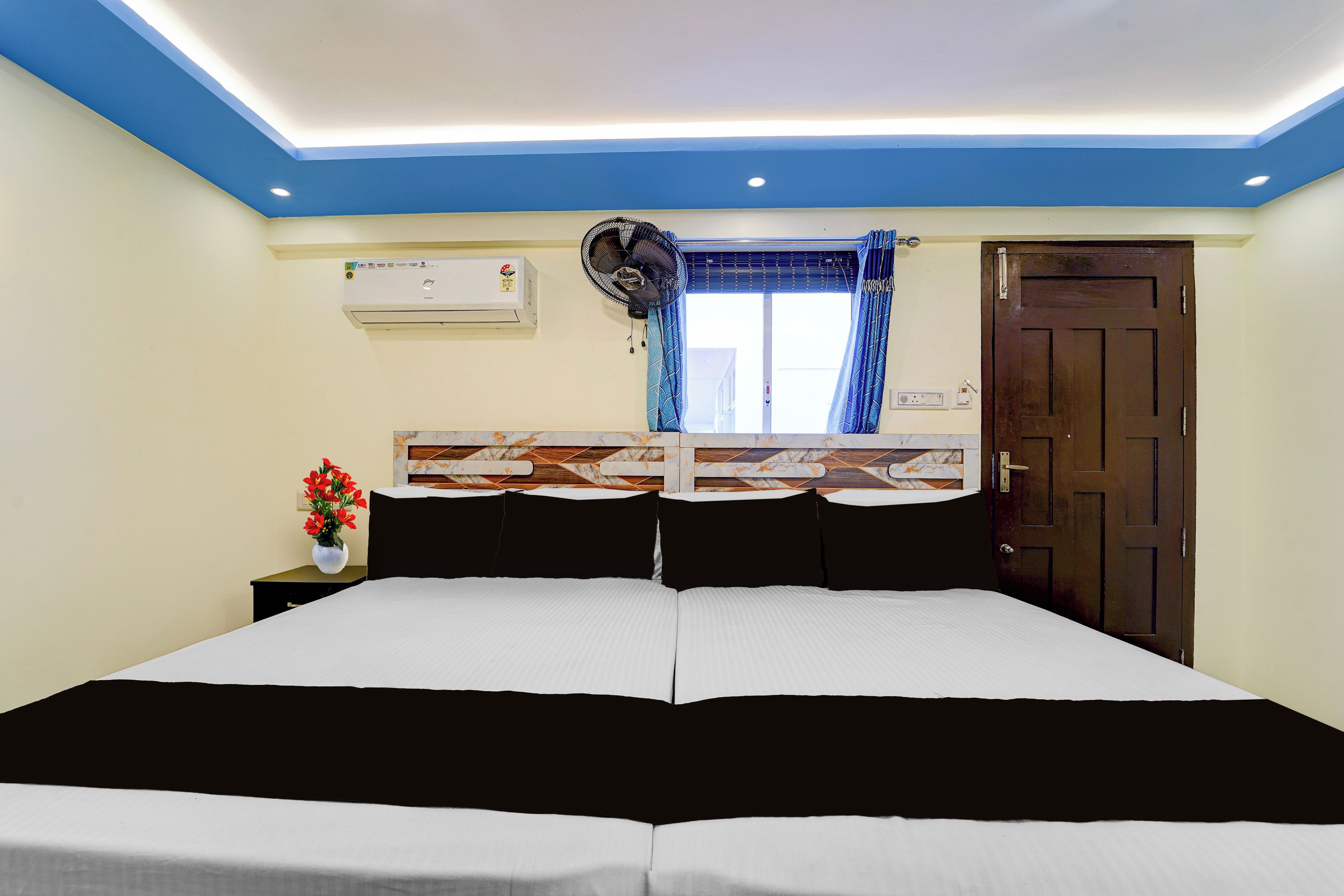 Habitación de hotel con una cama grande, una ventana con cortinas, un equipo de aire acondicionado y una puerta.