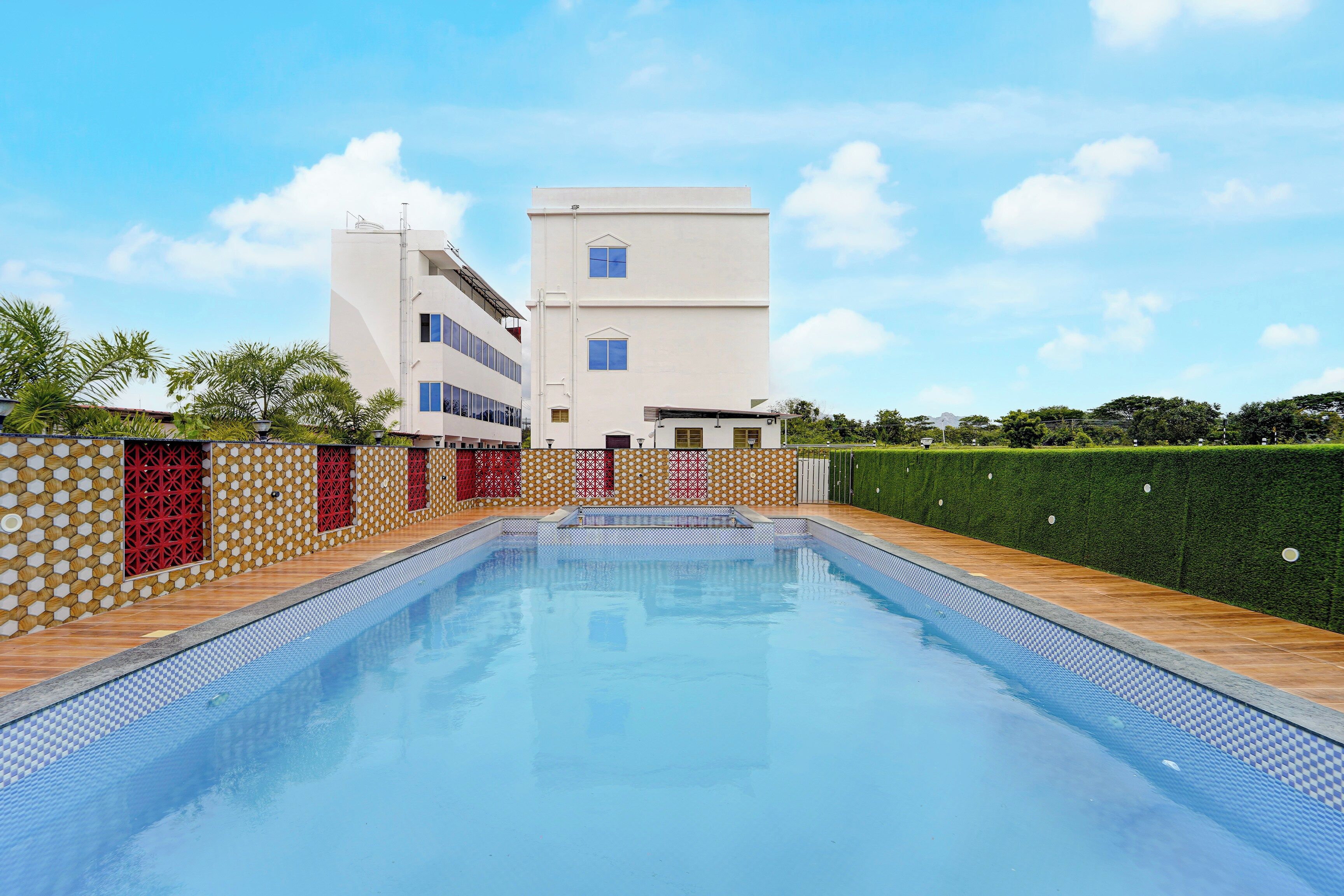 Una piscina con borde de azulejos, rodeada por una cubierta de madera y una pared con diseño.