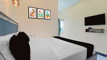 Una habitación de hotel con una cama, un televisor montado en la pared y tres cuadros enmarcados.